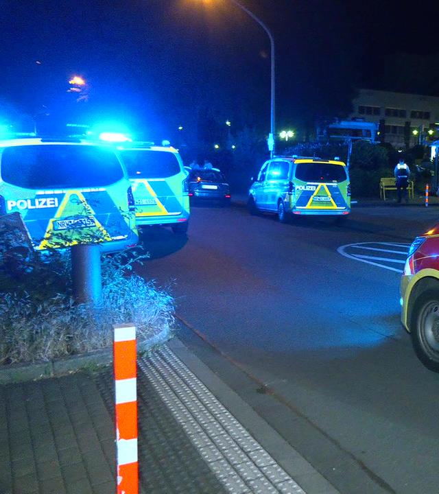 Ein Notarzt-Fahrzeug und mehrere Polizeiwagen stehen in der Nähe eines Tatorts in Essen.