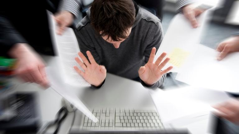 Ein Mitarbeiter in einem Büro in Hamburg ist mit zahlreichen Anforderungen konfrontiert. 