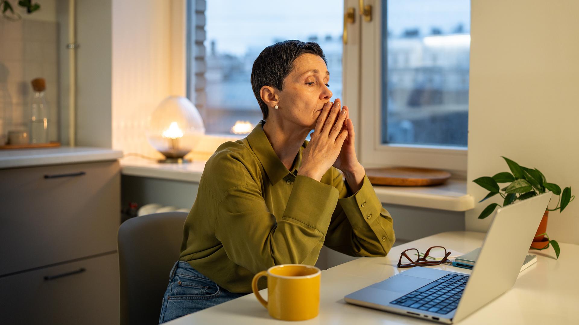Erschöpfte, nachdenkliche Geschäftsfrau, die unter Burnout am Arbeitsplatz leidet und mit Problemen zu kämpfen hat.