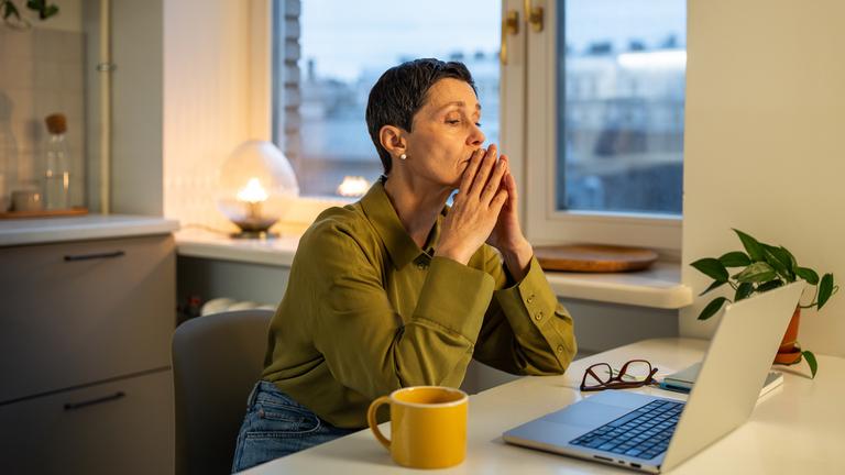 Erschöpfte, nachdenkliche Geschäftsfrau, die unter Burnout am Arbeitsplatz leidet und mit Problemen zu kämpfen hat.