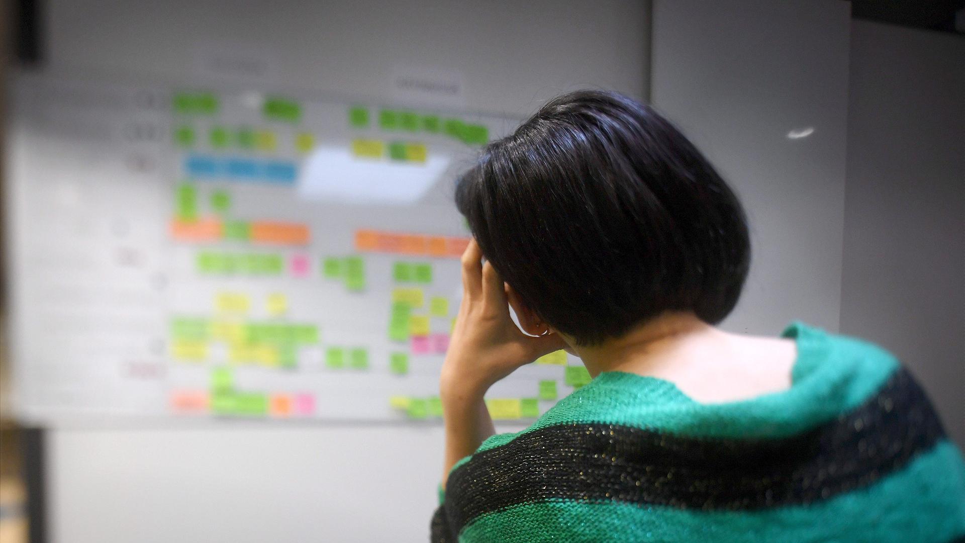 Frau sitzt gestresst vor Arbeitsplan in ihrem Büro