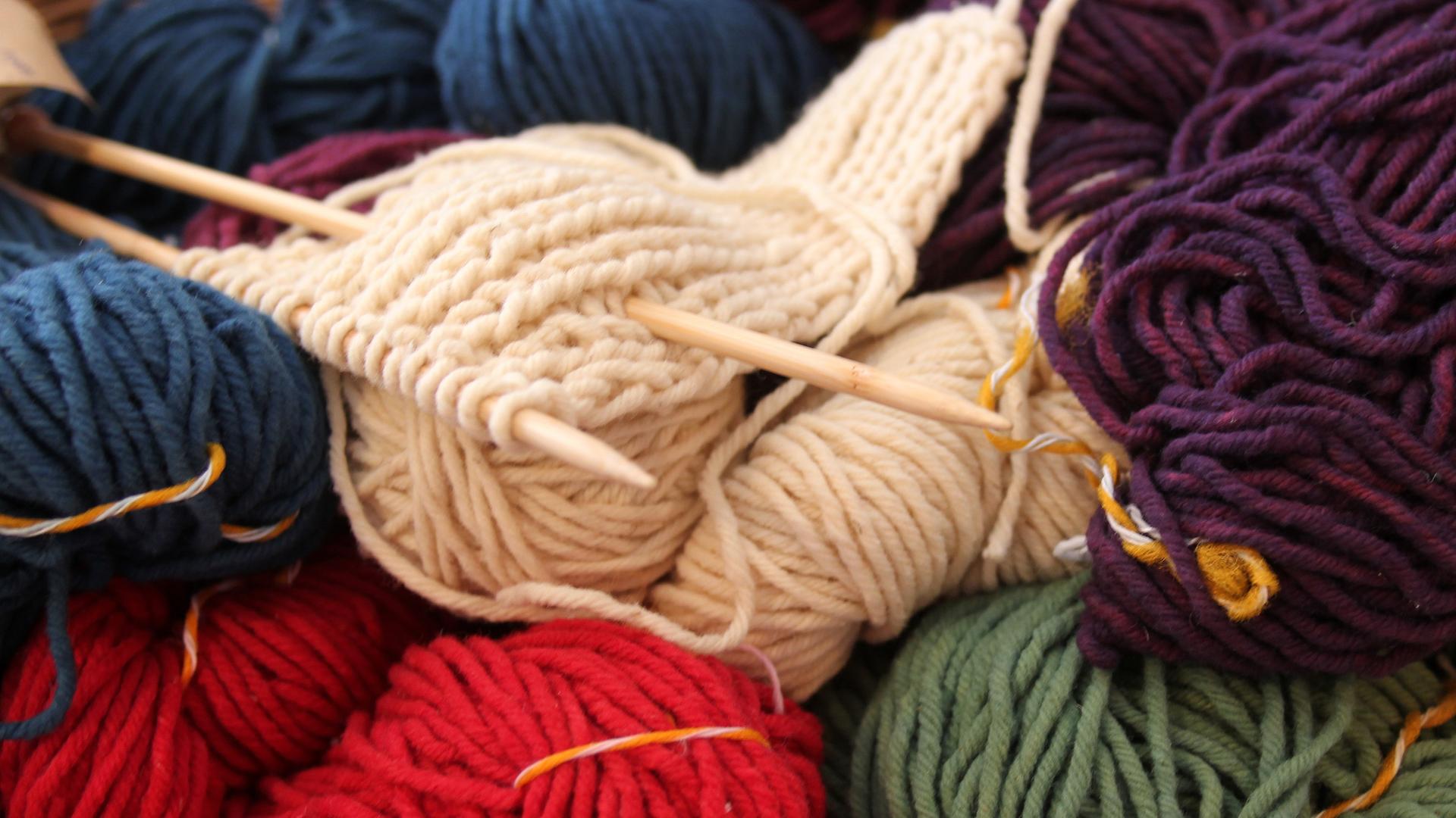 Mehrfarbige Wollknäuel mit Stricknadeln
