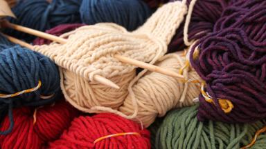 Mehrfarbige Wollknäuel mit Stricknadeln