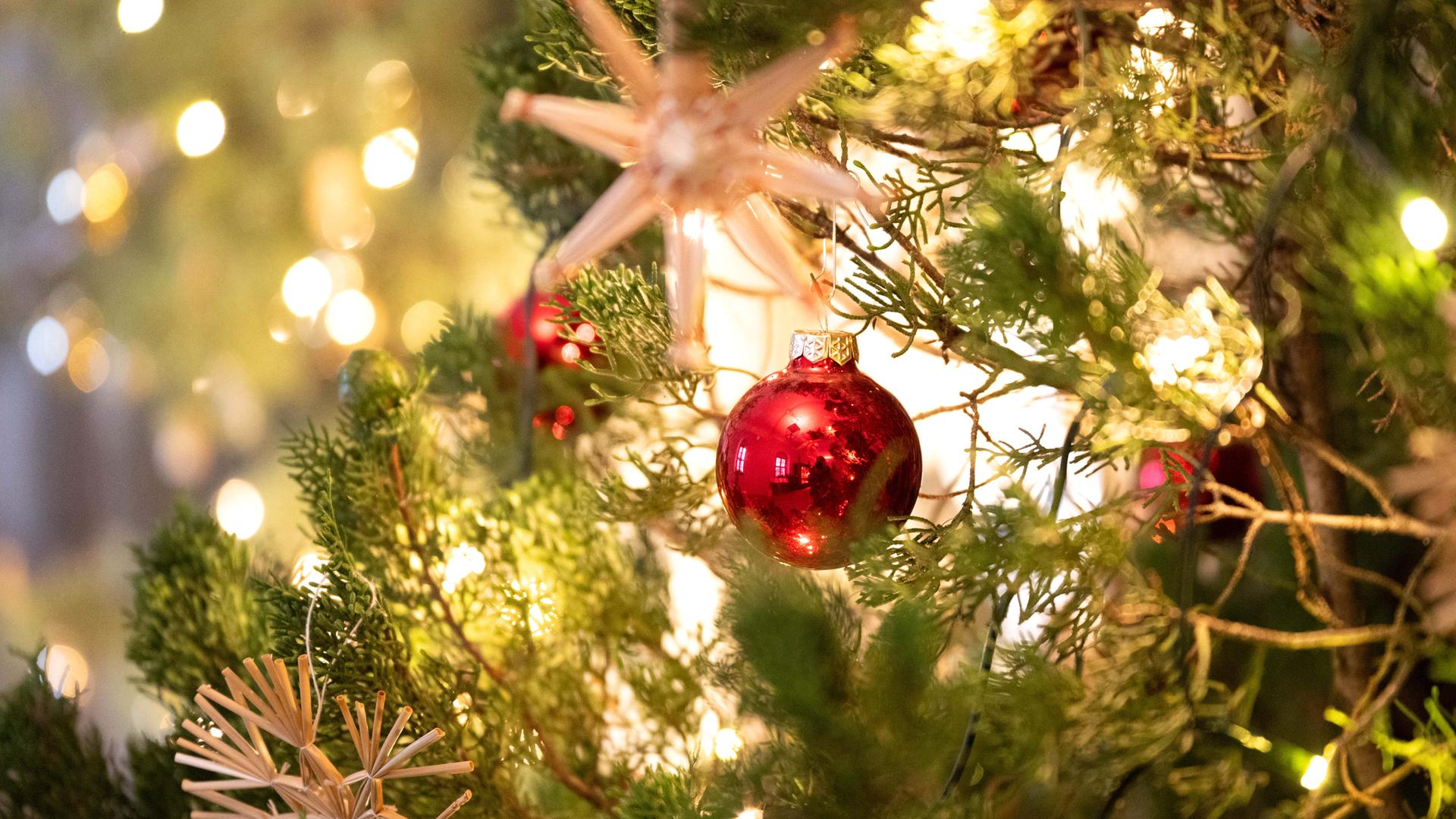 Ein Weihnachtsbaum ist mit Strohsternen und Weihnachtskugeln geschmückt