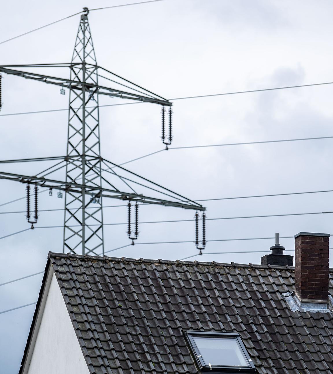 Ein Strommast steht hinter einem Wohnhaus.