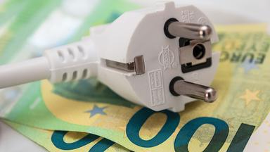 Ein Stromstecker auf zwei 100 Euro Geldscheinen.