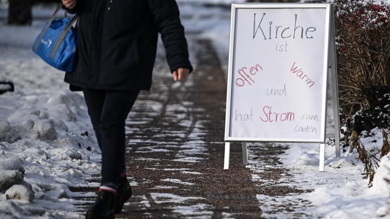 Auf einem Schild an einer Kirche steht Kirche ist offen warm und hat Strom zum Laden.