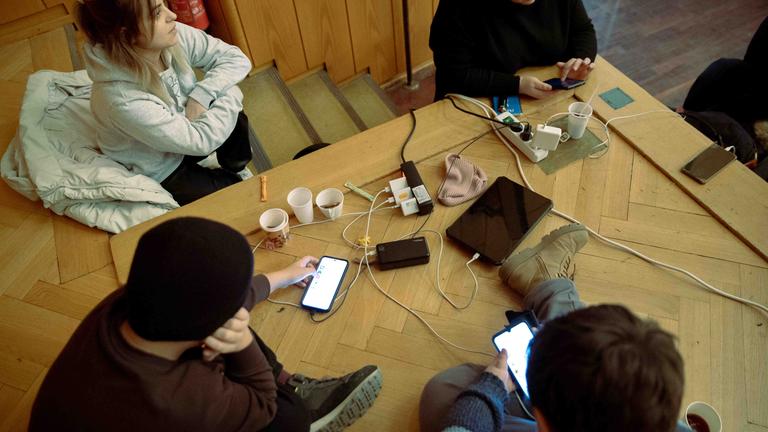 Verschiedene Hilfesuchende laden in Berlin in einer Notunterkunft ihre Telefone und andere Endgeräte