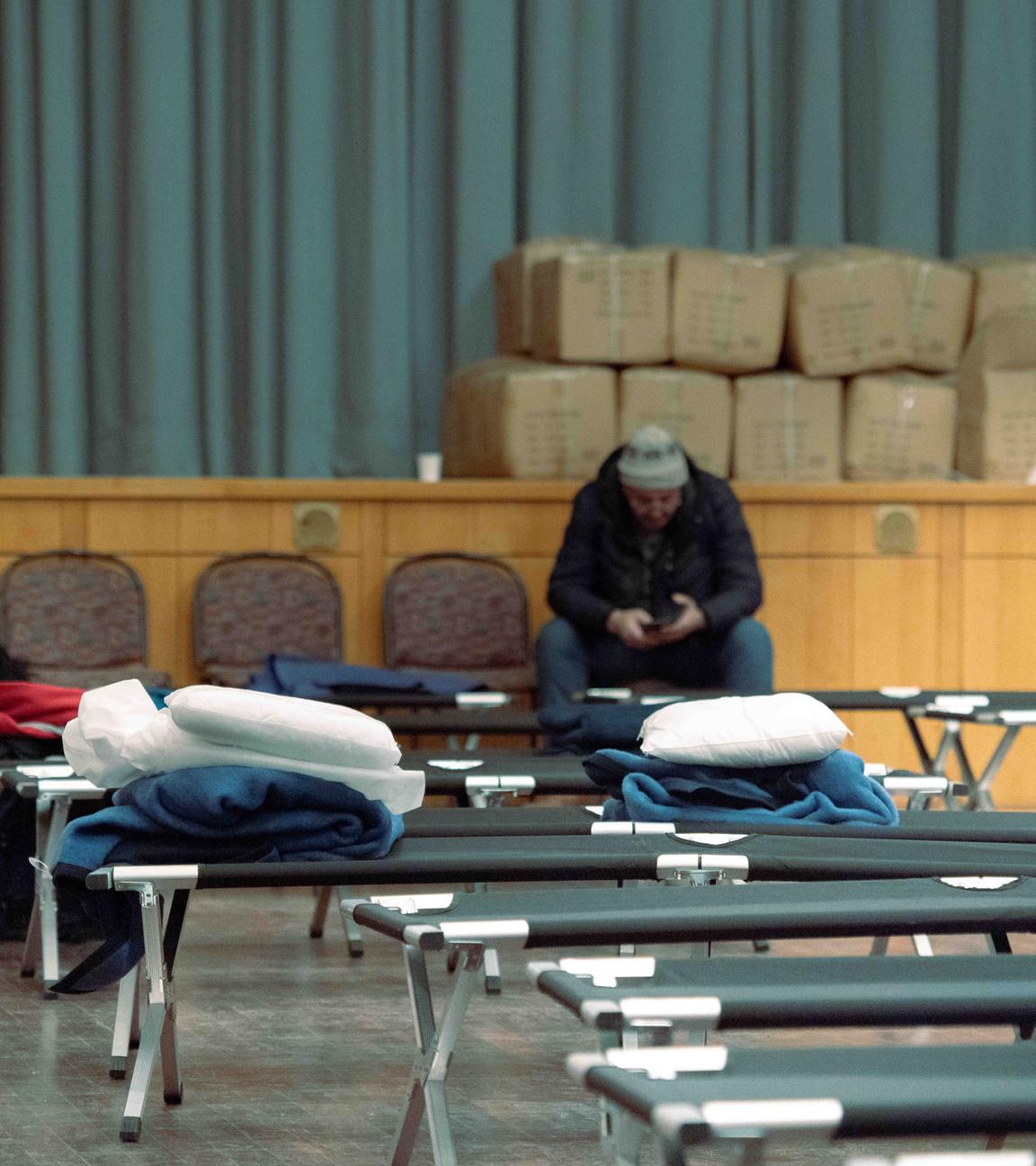 04.01.2026, Berlin: Hilfesuchende sitzen auf Stühlen hinter Feldbetten während eines Stromausfalls im Südwesten Berlins in einer Notunterkunft im Bürgersaal im Rathaus Zehlendorf. 