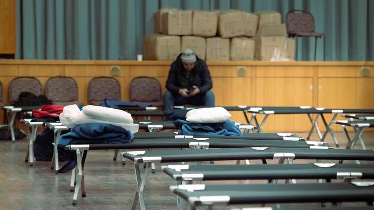 04.01.2026, Berlin: Hilfesuchende sitzen auf Stühlen hinter Feldbetten während eines Stromausfalls im Südwesten Berlins in einer Notunterkunft im Bürgersaal im Rathaus Zehlendorf. 