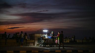 Ein Straßenverkäufer beleuchtet seine Waren mit einer tragbaren Lampe während eines landesweiten Stromausfalls an der Uferpromenade Malecón in Havanna.