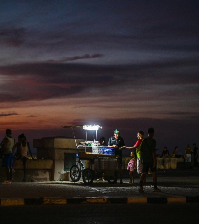 Ein Straßenverkäufer beleuchtet seine Waren mit einer tragbaren Lampe während eines landesweiten Stromausfalls an der Uferpromenade Malecón in Havanna.