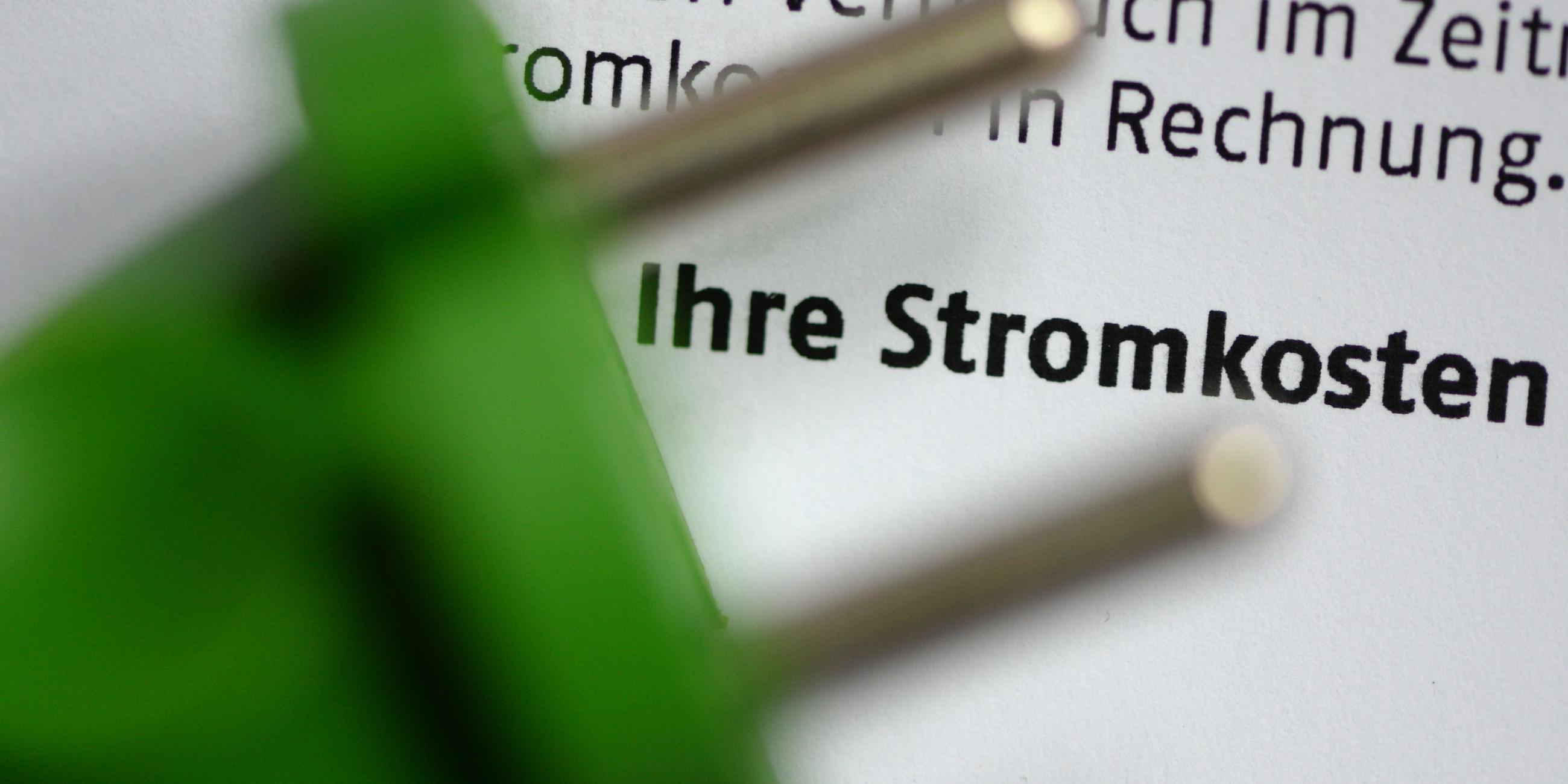Ein grüner Stromstecker liegt auf einer Stromrechnung.