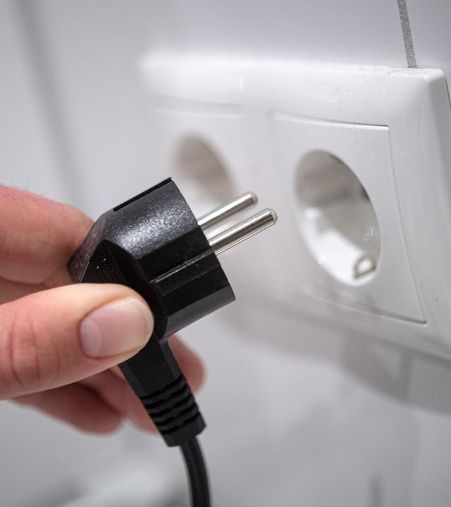 Strompreis, Symbolbild. Ein Stecker wird in eine Steckdose gesteckt. 