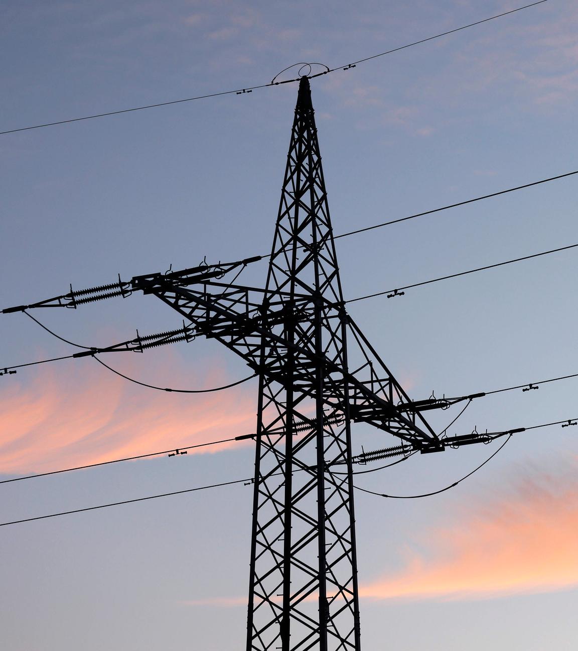 Ein Strommast mit Stromleitung steht im Abendlicht auf einem Feld am 10.01.2025 in Neustadt, Wied.