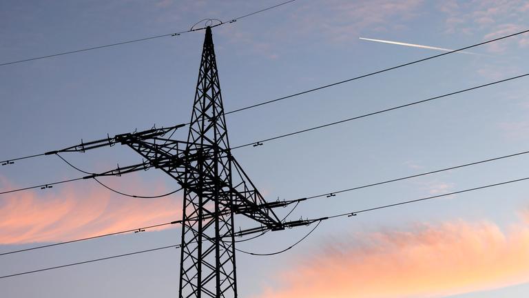 Ein Strommast mit Stromleitung steht im Abendlicht auf einem Feld am 10.01.2025 in Neustadt, Wied.