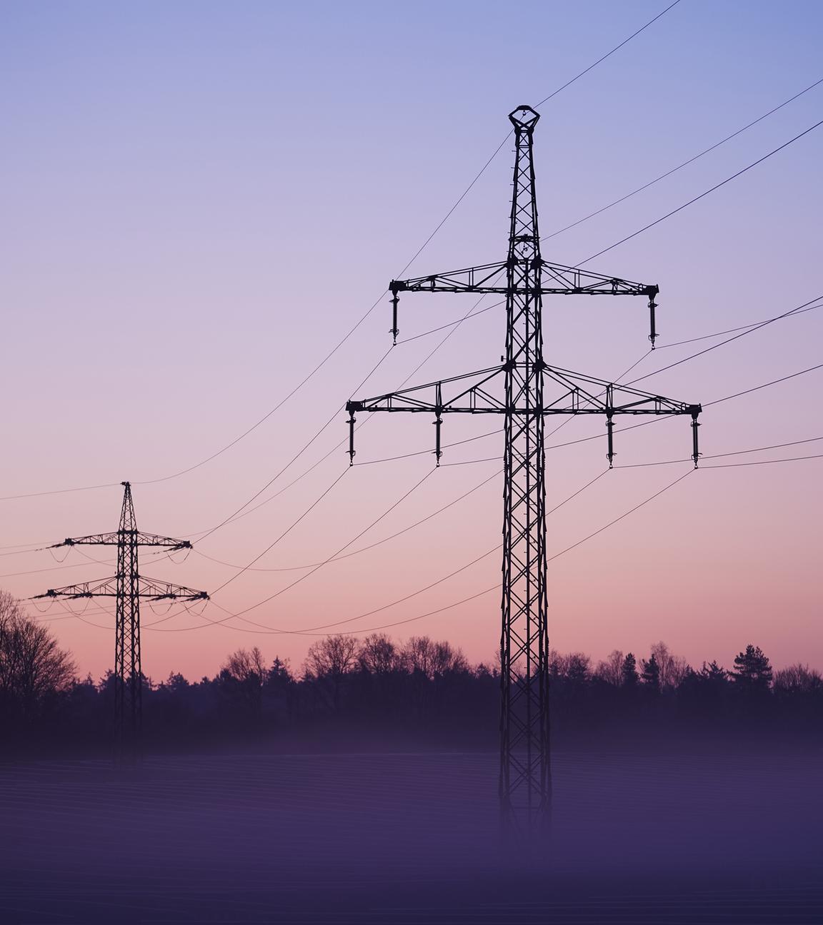 28.03.2022, Bayern, Buckendorf: Nebel zieht über ein Solarfeld mit darüber laufender Stromleitungen.