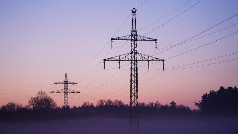 28.03.2022, Bayern, Buckendorf: Nebel zieht über ein Solarfeld mit darüber laufender Stromleitungen.