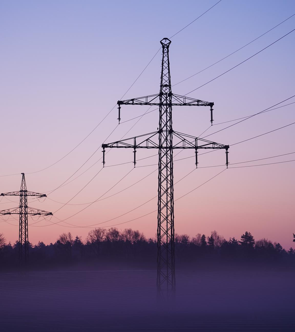 Nebel zieht über ein Solarfeld mit darüber laufender Stromleitungen.