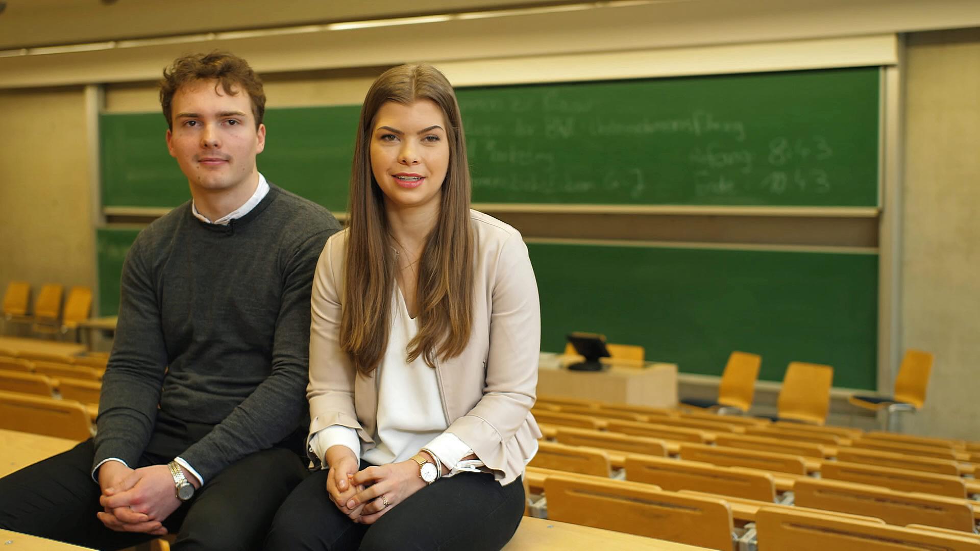 Student Robin und Studentin Vivien sitzen im leeren Hörsaal.