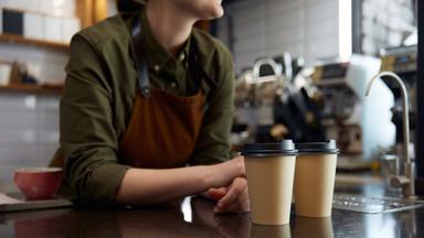 Eine weibliche Barista mit zwei Bechern Coffee to go.