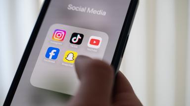 24.10.2024, Niedersachsen, Hannover: Eine Frau hält ein Smartphone, auf dessen Display verschiedene Social Media Apps angezeigt werden. 