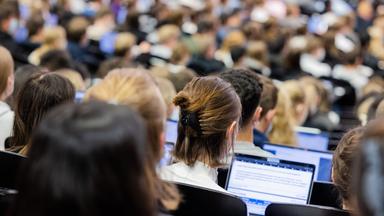 Studentinnen und Studenten sitzen während einer Vorlesung in einem Hörsaal.