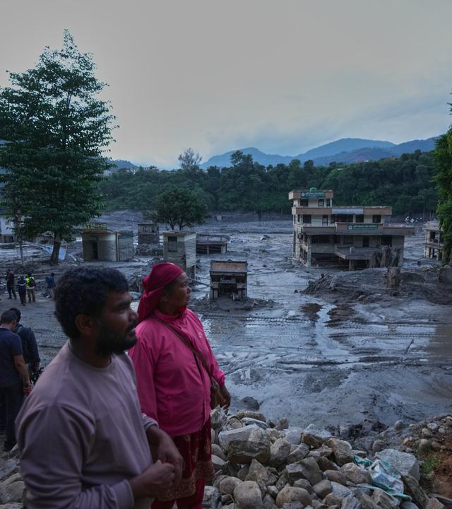  Anwohner betrachten die Verwüstungen, die Sturzfluten im nepalesischen Distrikt Nuwakot hinterlassen haben.