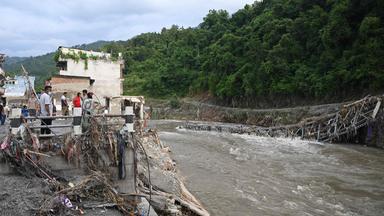 Nepal: Menschen stehen neben einer durch die Sturzflut eingerissene Brücke.