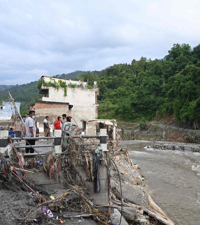 Nepal: Menschen stehen neben einer durch die Sturzflut eingerissene Brücke.