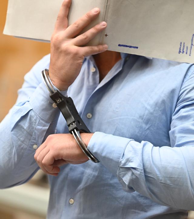 Einer der Angeklagten in einem Staatsschutzverfahren gegen drei Ukrainer wegen Agententätigkeit im Auftrag eines russischen Nachrichtendienstes kommt in Handschellen in den Saal