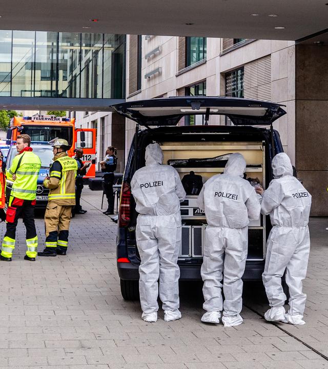 Beamte der Spurensicherung stehen bei einem größeren Polizeieinsatz vor einem Einkaufszentrum in der Innenstadt.