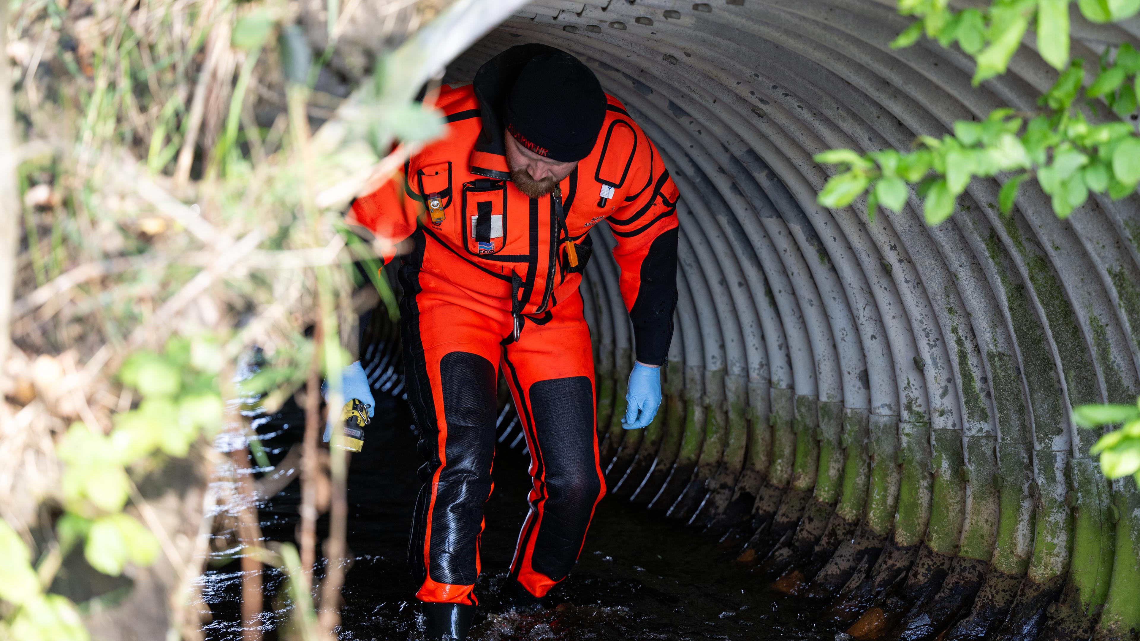 Ein Feuerwehrmann sucht in einem Rohr mit Wasser nach dem vermissten Jungen Arian. 