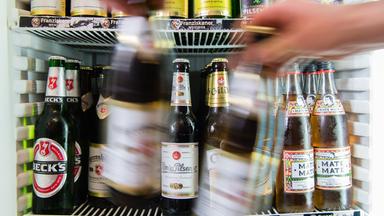 Symbolfoto: Ein mann  nimmt zwei flaschen Bier aus einem Kühlschrank.