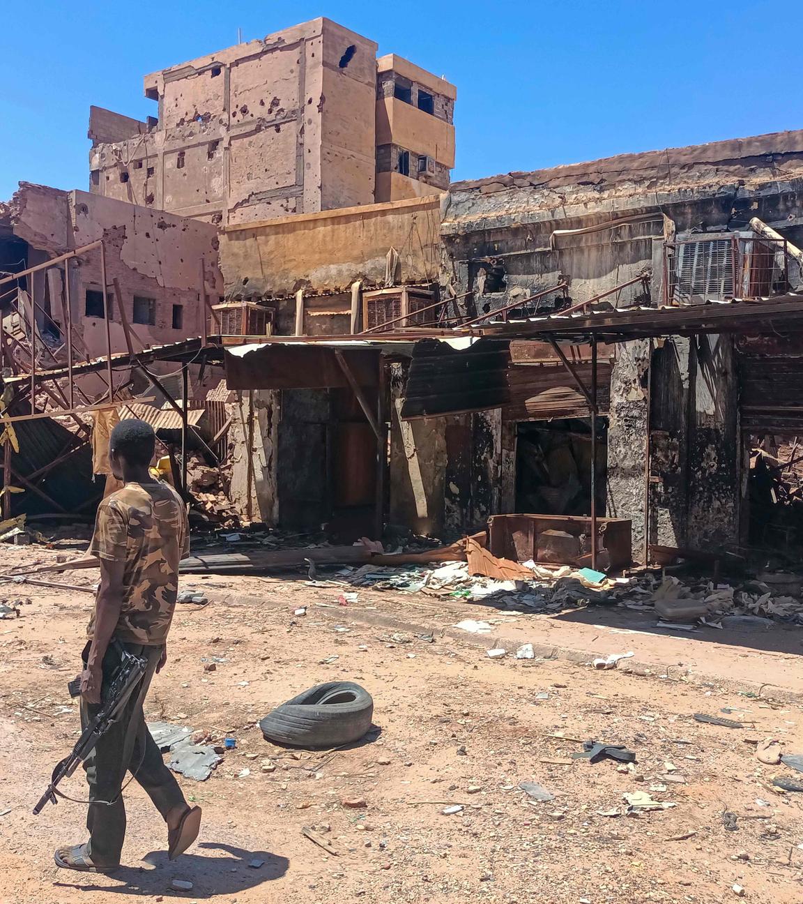 Ein bewaffneter Kämpfer patrouilliert in einem Marktgebiet in Khartum, während der Krieg im Sudan zwischen Armee und RSF große Zerstörung und humanitäre Krise verursacht.