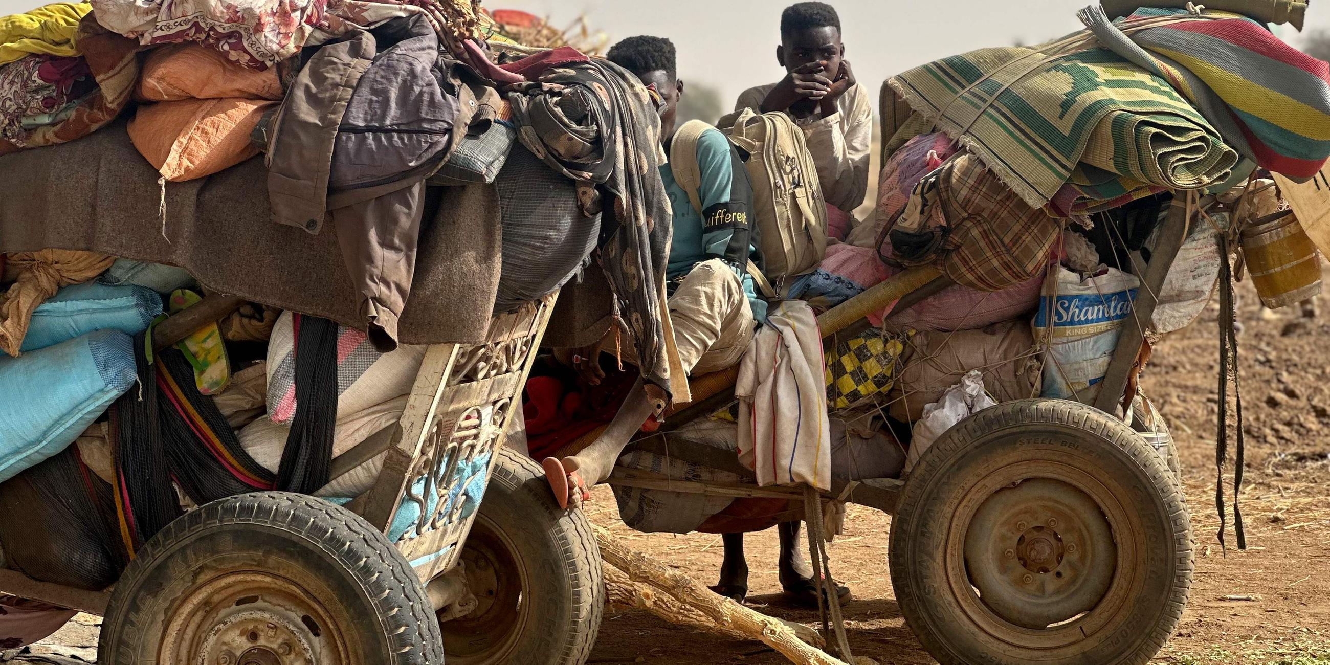 Flüchtende Menschen sitzen auf einem Wagen im Sudan.