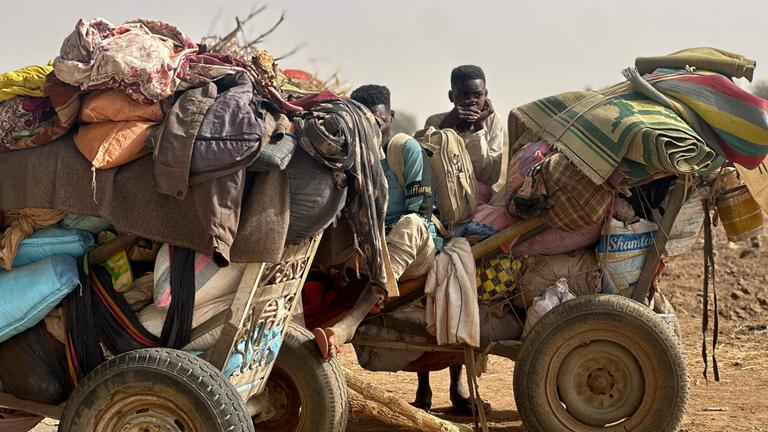 Flüchtende Menschen sitzen auf einem Wagen im Sudan.