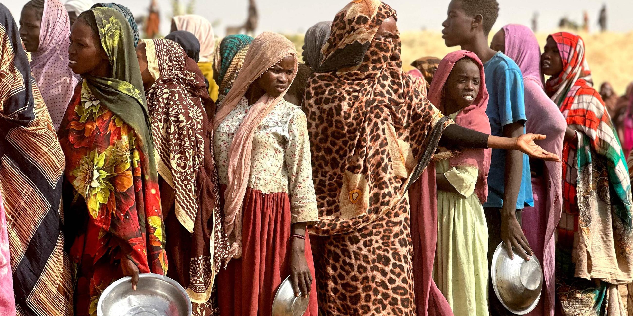 Menschen stehen in einem provisorischen Lager auf einem offenen Feld nahe der sudanesischen Stadt Tawila für Lebensmittelrationen Schlange