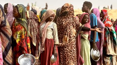 Menschen stehen in einem provisorischen Lager auf einem offenen Feld nahe der sudanesischen Stadt Tawila für Lebensmittelrationen Schlange