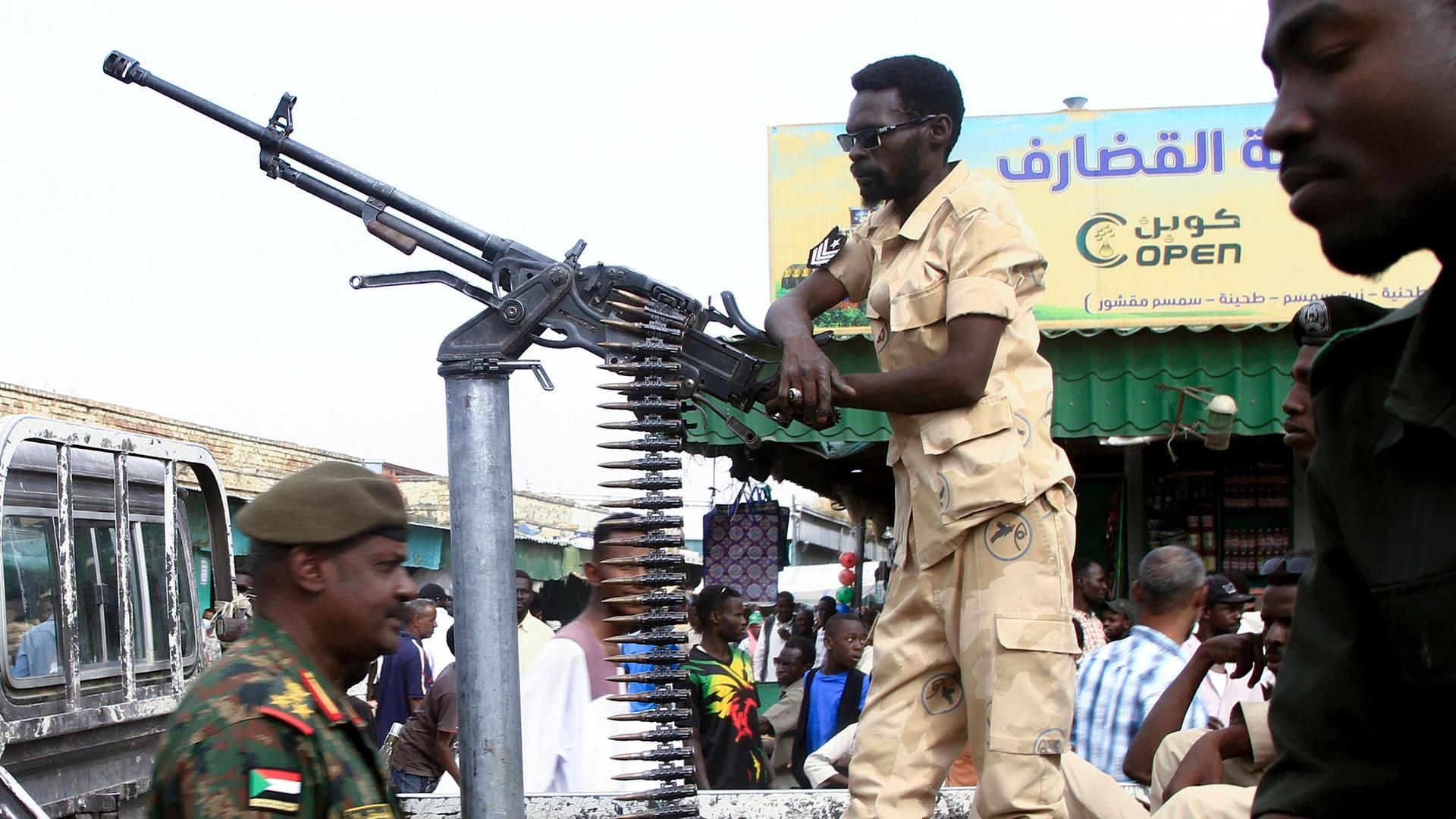 Es sind Soldaten der Miliz in Sudan zu sehen. Einer der Männer stützt sich an einem Standgeschützt ab.
