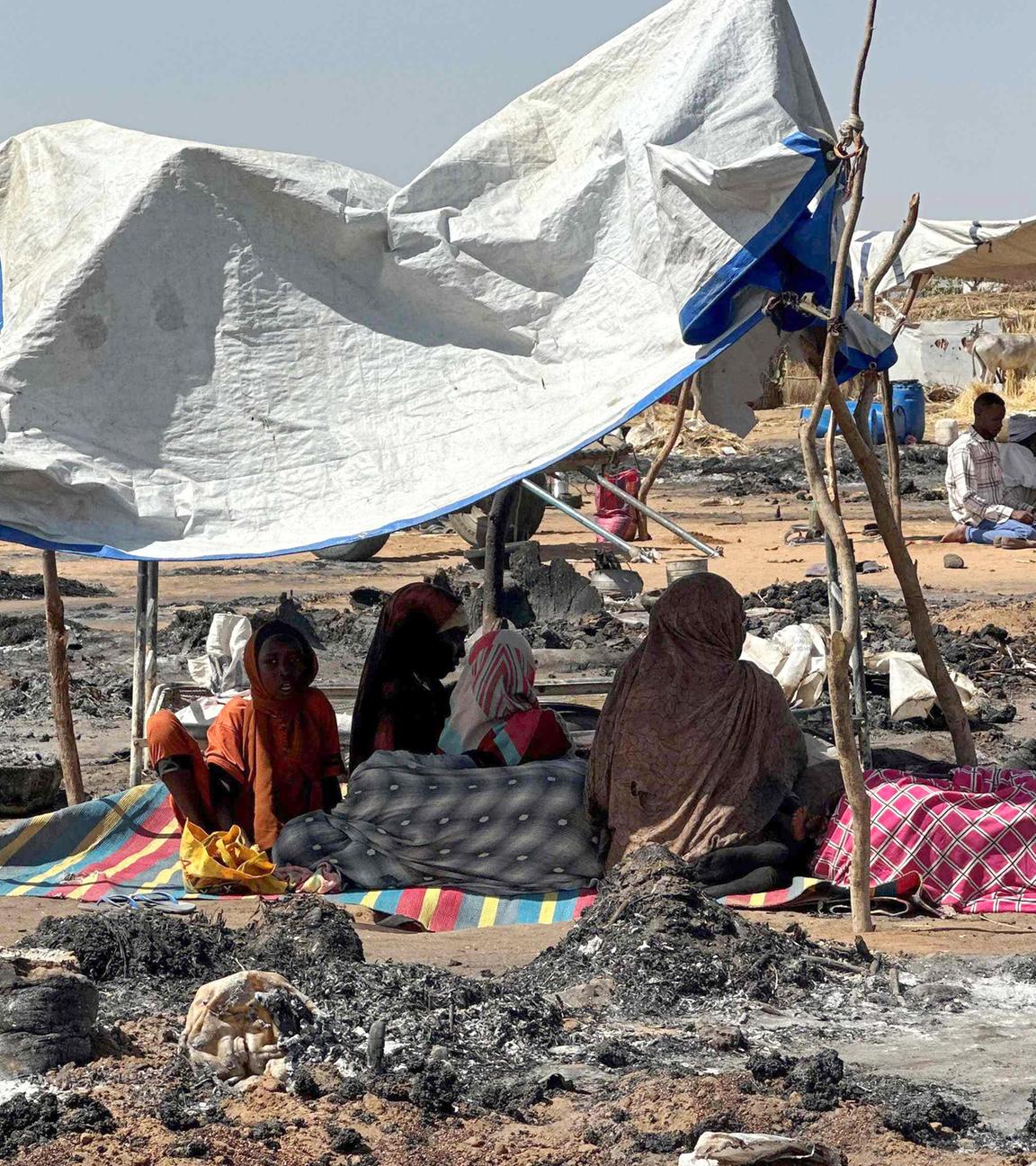 Vertriebene Sudanesen, die nach dem Fall von El-Fasher das Lager verlassen haben, sitzen im Schatten von Tawila inmitten der Überreste eines Brandes