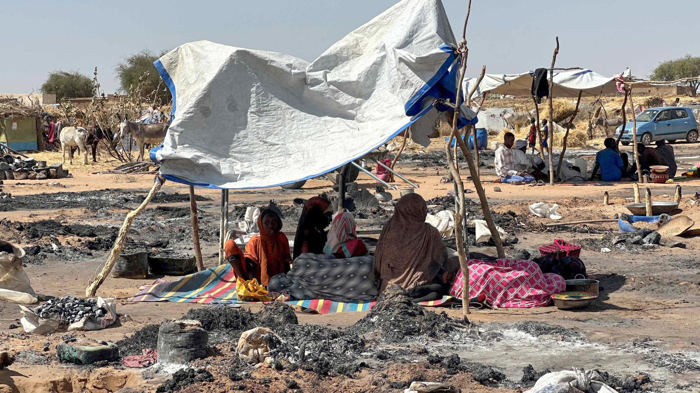 Vertriebene Sudanesen, die nach dem Fall von El-Fasher das Lager verlassen haben, sitzen im Schatten von Tawila inmitten der Überreste eines Brandes