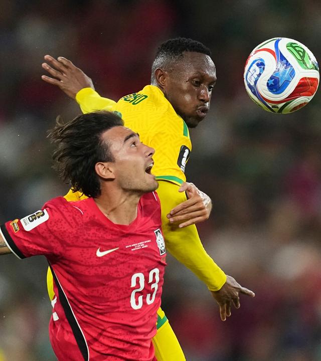 Der Südkoreaner Jens Castrop (l, 23) springt gemeinsam mit dem Südafrikaner Thapelo Maseko (12) zum Ball. 