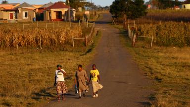 Feldweg in Südafrika, dei Frauen laufen weg entlang