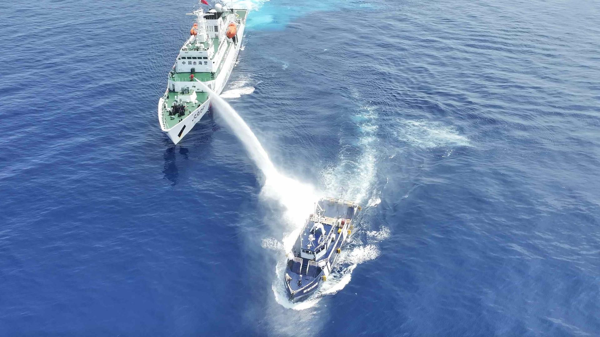 Zwei Schiffe auf hoher See: das größere beschießt das kleinere mit einem starken Wasserwerfer.