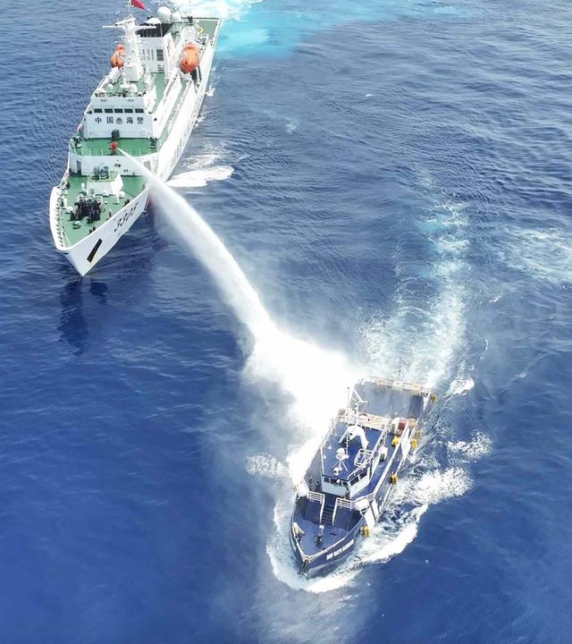Zwei Schiffe auf hoher See: das größere beschießt das kleinere mit einem starken Wasserwerfer.