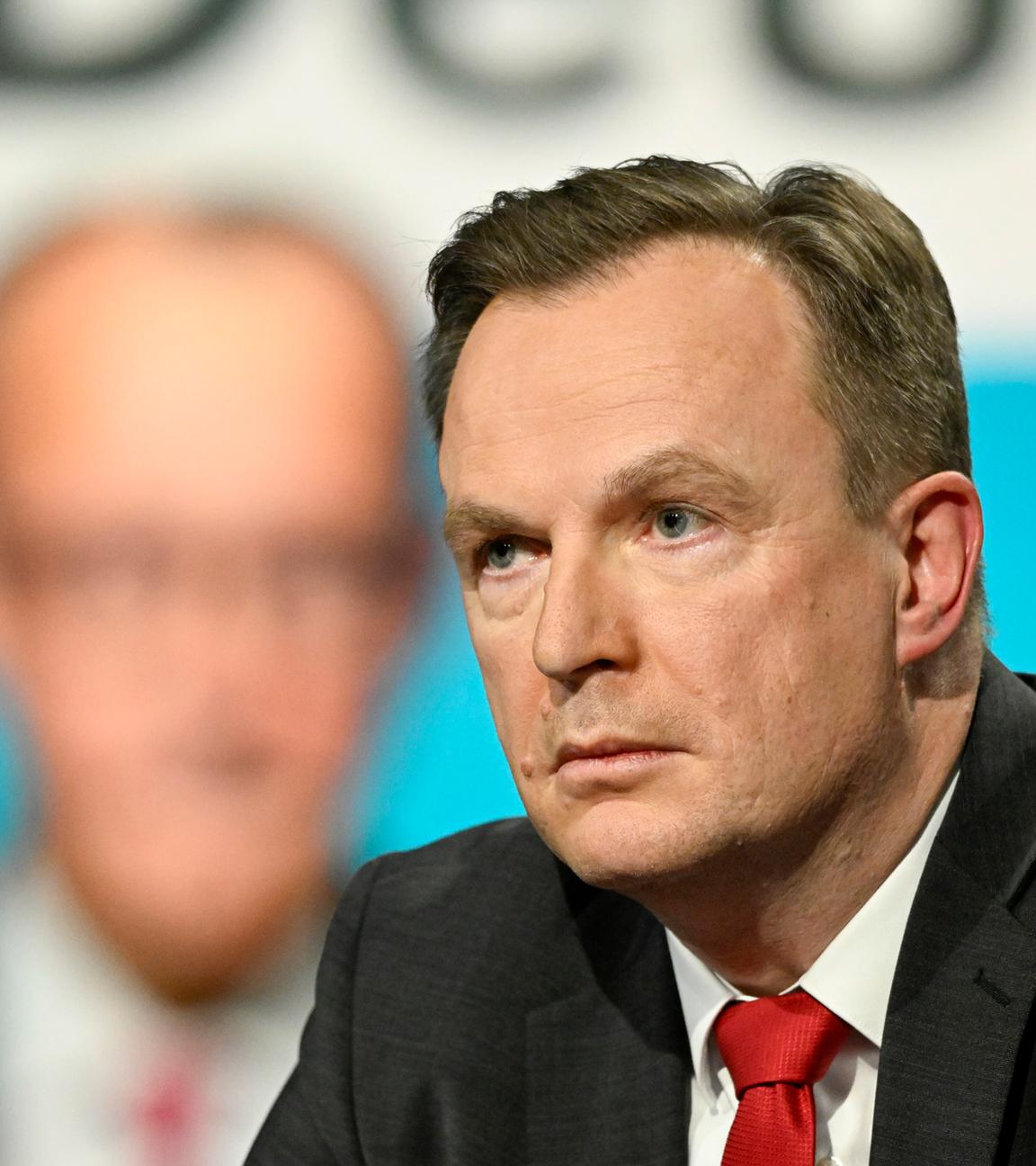 Jens Südekum in der Sendung "Markus Lanz", im Hintergrund ein verschwommenes Bild von Friedrich Merz