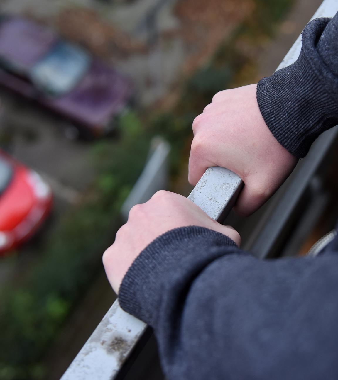 Gelsenkirchen: Ein junges Mädchen hält sich am Geländer eines Balkones fest.