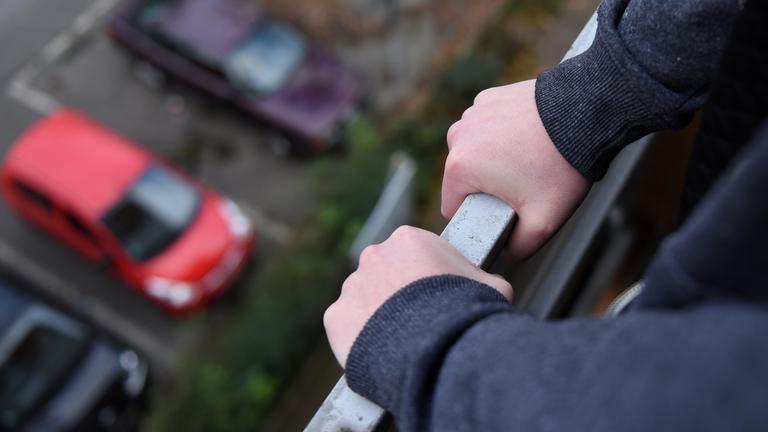Gelsenkirchen: Ein junges Mädchen hält sich am Geländer eines Balkones fest.