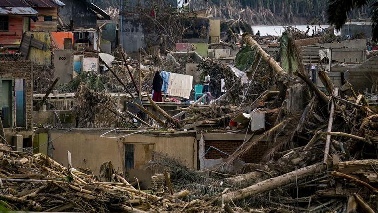 Eine Frau hängt frisch gewaschene Wäsche inmitten der verheerenden Schäden auf, die durch die Sturzflut verursacht wurden, die das Gebiet in Aceh Tamiang, Provinz Aceh, am 6. Dezember 2025 heimgesucht hat.